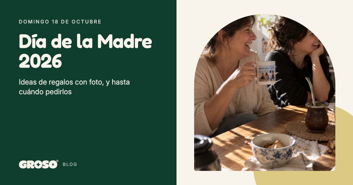 Madre e hija se ríen en la cocina; la madre sostiene una taza con una foto de la familia en la playa