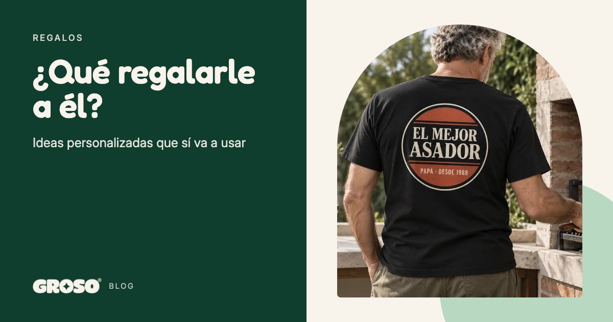 Un hombre de espaldas haciendo un asado, con una remera negra que lleva estampado un escudo de asador en la espalda